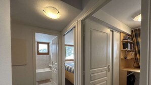 A narrow hallway with a bathroom on the left, a bed in the middle, and a bookshelf on the right. - Duplex chalet 6-8 ppl, garage, WiFi, Montgenèvre (Montgenèvre)