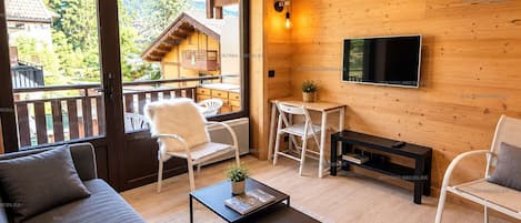 Una sala de estar acogedora con un sofá, sillones, una mesa de centro y un televisor.