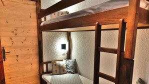 A bunk bed with a ladder, a small bedside table, and a wall-mounted light fixture.