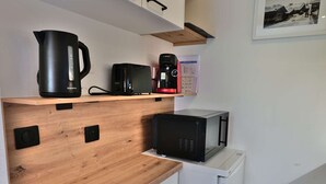 A kitchenette with a wooden countertop, a coffee maker, a toaster, a kettle, and a microwave.
