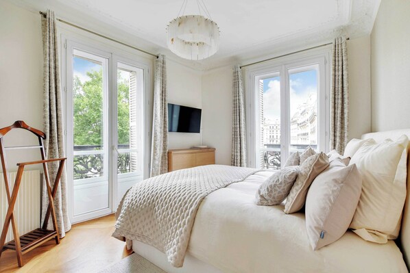 A bedroom with a bed, a TV, and a balcony.