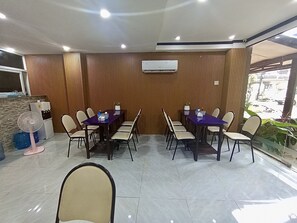 A conference room with a long table and chairs, an air conditioning unit on the wall, and a window with a view of the outside.