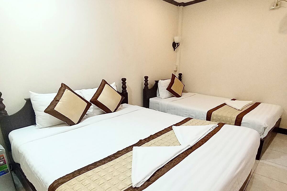 A hotel room with two single beds, each with a wooden headboard and white bedding.
