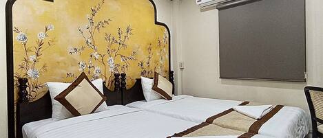 A hotel room with two beds, a large decorative headboard, and an air conditioning unit on the wall.