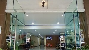 A modern building entrance with glass doors, a stone-tiled pathway, and indoor seating areas visible through the glass. - Memory Hotel Vientiane  (Vientiane)