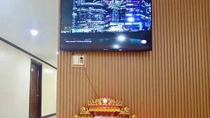 A shrine with offerings, a television mounted on a wooden wall, and a tiled floor in a hallway. - Memory Hotel Vientiane  (Vientiane)