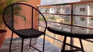 A balcony with a metal chair and table, potted plants, and a view of neighboring buildings. - R-Oak Hotels and Apartments  (Abuja)