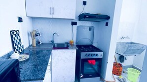 A compact kitchen with white cabinets, a gas stove, a built-in oven, and a small sink. - Classy One bed airbnb by Miss Omuts,pool (Nairobi)