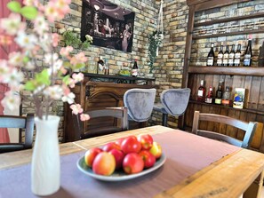 A restaurant interior with a brick wall, a bar area with bottles, and a table with a plate of apples.