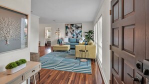 A modern living room with a sofa, a coffee table, and a painting on the wall. - Modern 4BR Home w/ Private Heated Pool & Firepit (Seminole)