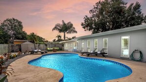 A backyard with a swimming pool, lounge chairs, and a covered patio area. - Modern 4BR Home w/ Private Heated Pool & Firepit (Seminole)