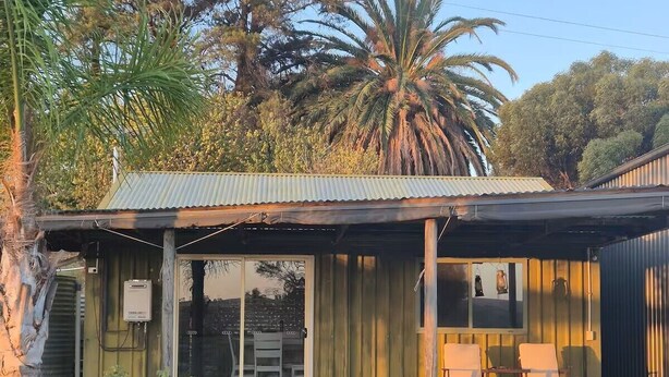 A small building with a metal roof, a glass door, and a patio with two chairs. - Tipsy Hill Cottage, River Views at Walker Flat SA. Perfect for a weekend getaway (Forster)
