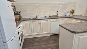 A kitchen with white cabinets, a dishwasher, a stove, and a sink. - Tipsy Hill Cottage, River Views at Walker Flat SA. Perfect for a weekend getaway (Forster)
