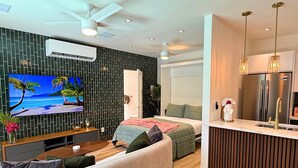 Ein modernes Wohnzimmer mit Fernseher, Sofa und Essbereich.