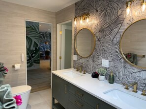 Une salle de bain moderne avec un grand miroir, deux lavabos et un meuble-lavabo doté de tiroirs.