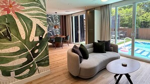 Ein modernes Wohnzimmer mit einer gebogenen Couch, einem runden Couchtisch und einem Essbereich mit Tisch und Stühlen.