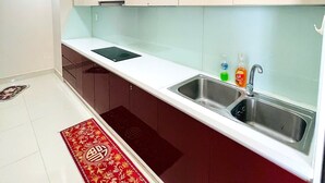 Ett modernt kök med vita skåp, en diskho i rostfritt stål och en röd, mönstrad matta på golvet.