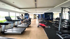Ett gym med löpband, styrketräningsmaskiner och en vägg full med speglar.