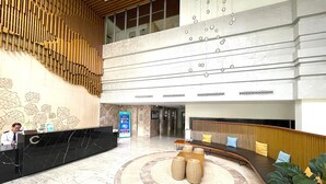 En hotellobby med en receptionsdisk, en sittgrupp med en rund matta och en stor växt.