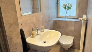 A bathroom with a sink, toilet, and a window with a decorative view.