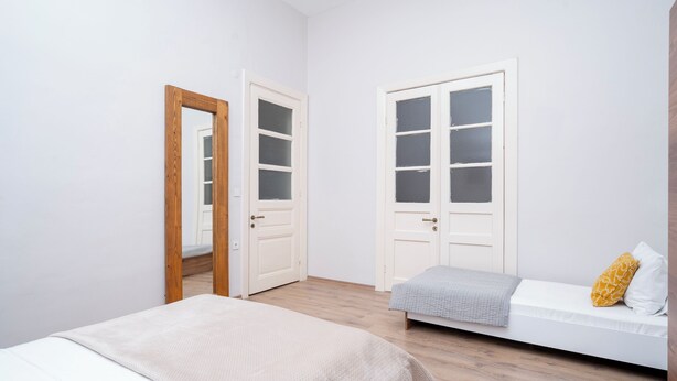 A minimalist bedroom with a bed, a sofa, and two doors. - 3-Bedroom, 2-Bathroom with High Ceilings, Spacious Layout and No Stairs (İstanbul)