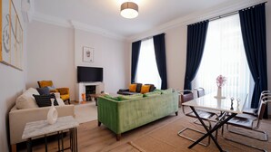 A modern living room with a green sofa, a white coffee table, and a dining area with a white table and chairs. - 3-Bedroom, 2-Bathroom with High Ceilings, Spacious Layout and No Stairs (İstanbul)