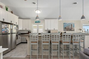 A modern kitchen with white cabinetry, stainless steel appliances, and a central island with bar stools.