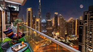 A balcony with a view of a city skyline, including a prominent skyscraper, at night. - Gogoto LUX Burj View Spacious (Dubai)