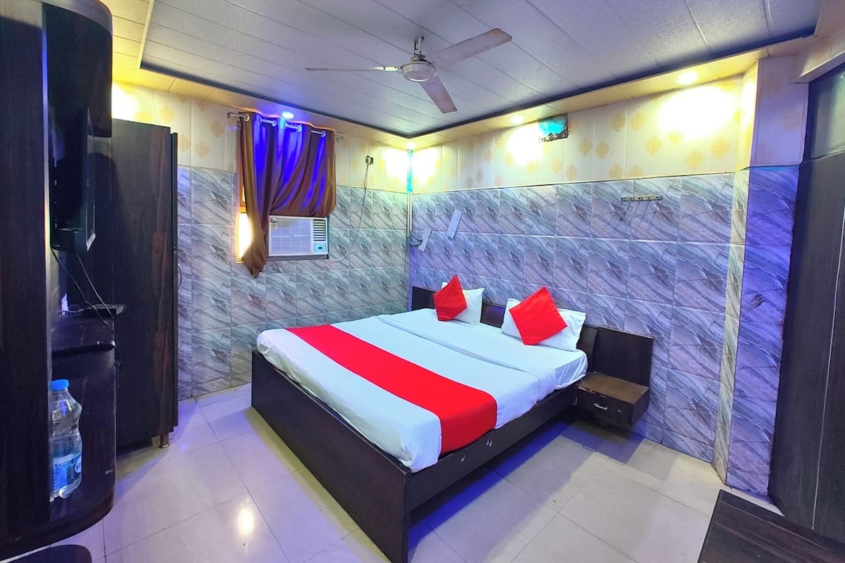 Une chambre d’hôtel équipée d’un lit, d’un ventilateur de plafond, d’un distributeur d’eau et d’un espace douche.