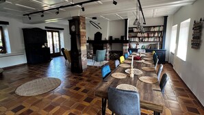 A spacious dining area with a long wooden table, multiple chairs, and a large bookshelf filled with books. - New home! La Buissonnière, 12 to 14 pers with Spa, 45min from Strasbourg. (Erckartswiller)