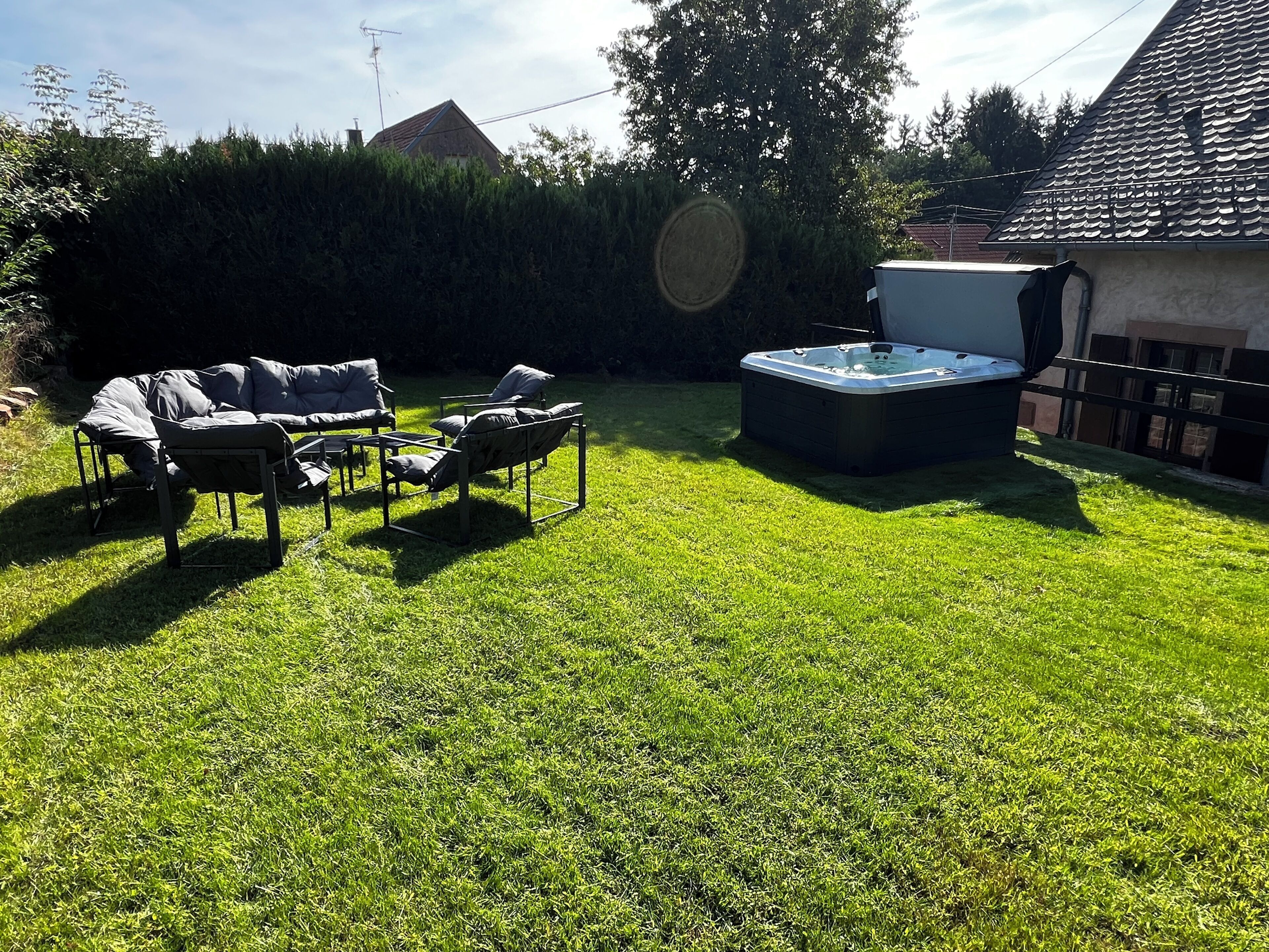 A backyard with a hot tub, outdoor furniture, and a well-maintained lawn.