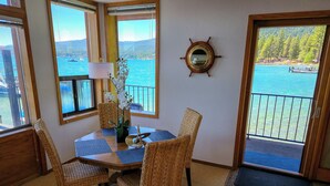 A dining area with wicker chairs, a wooden table, and a view of a lake through large windows. - Tahoe Vista Inn Suite 2 (Tahoe Vista)