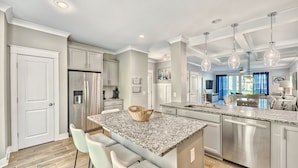 A modern kitchen with granite countertops, stainless steel appliances, and a central island with bar stools. - 42 Sandcastle | Free Heated Pool | 3 Blocks to the Beach | Elevator (Hilton Head Island)