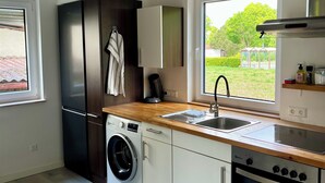 A modern kitchen with a washing machine, a built-in oven, and a sink. - Schwabenperle Apartments  (Laucheim)