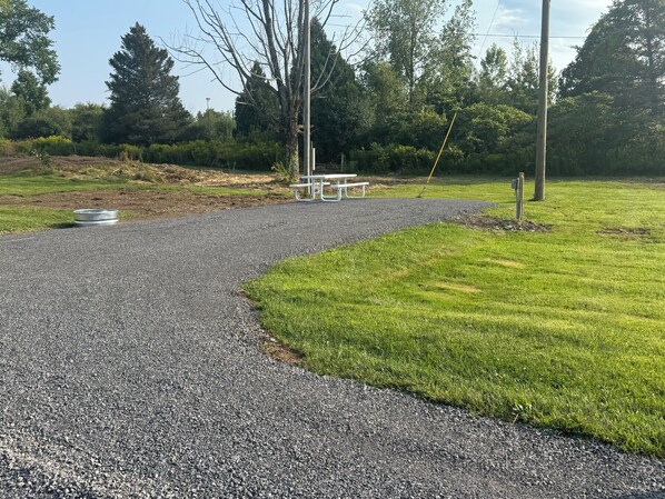 Un sendero de grava que conduce a una mesa de picnic rodeada de césped y árboles.