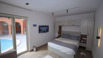 Un dormitorio moderno con una cama grande, armario empotrado y puerta corrediza de vidrio que da a una zona de piscina.