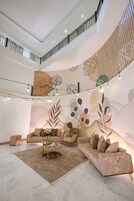 A spacious living area with a high ceiling, a staircase, and a decorative wall mural.