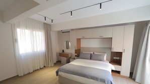 Une chambre moderne avec un grand lit, une armoire intégrée, des tables de chevet et un miroir.