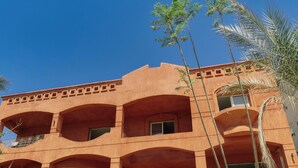 Un immeuble à plusieurs étages, doté d’une façade symétrique, de grandes fenêtres et d’une entrée fermée par un portail.