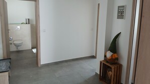 A hallway with a wooden door, a small framed picture, and a potted plant. - Modern vacation apartment in Kehl, 60m2 comfort on one level (Weißenburg in Bayern)