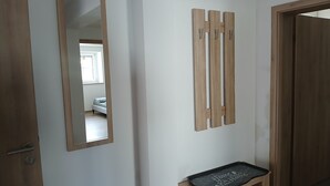 A hallway with a wooden door, a mirror, and a wooden bench with a tray. - Modern vacation apartment in Kehl, 60m2 comfort on one level (Weißenburg in Bayern)