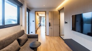 Un pasillo moderno de hotel con un sofá, una mesita y un televisor montado en la pared.