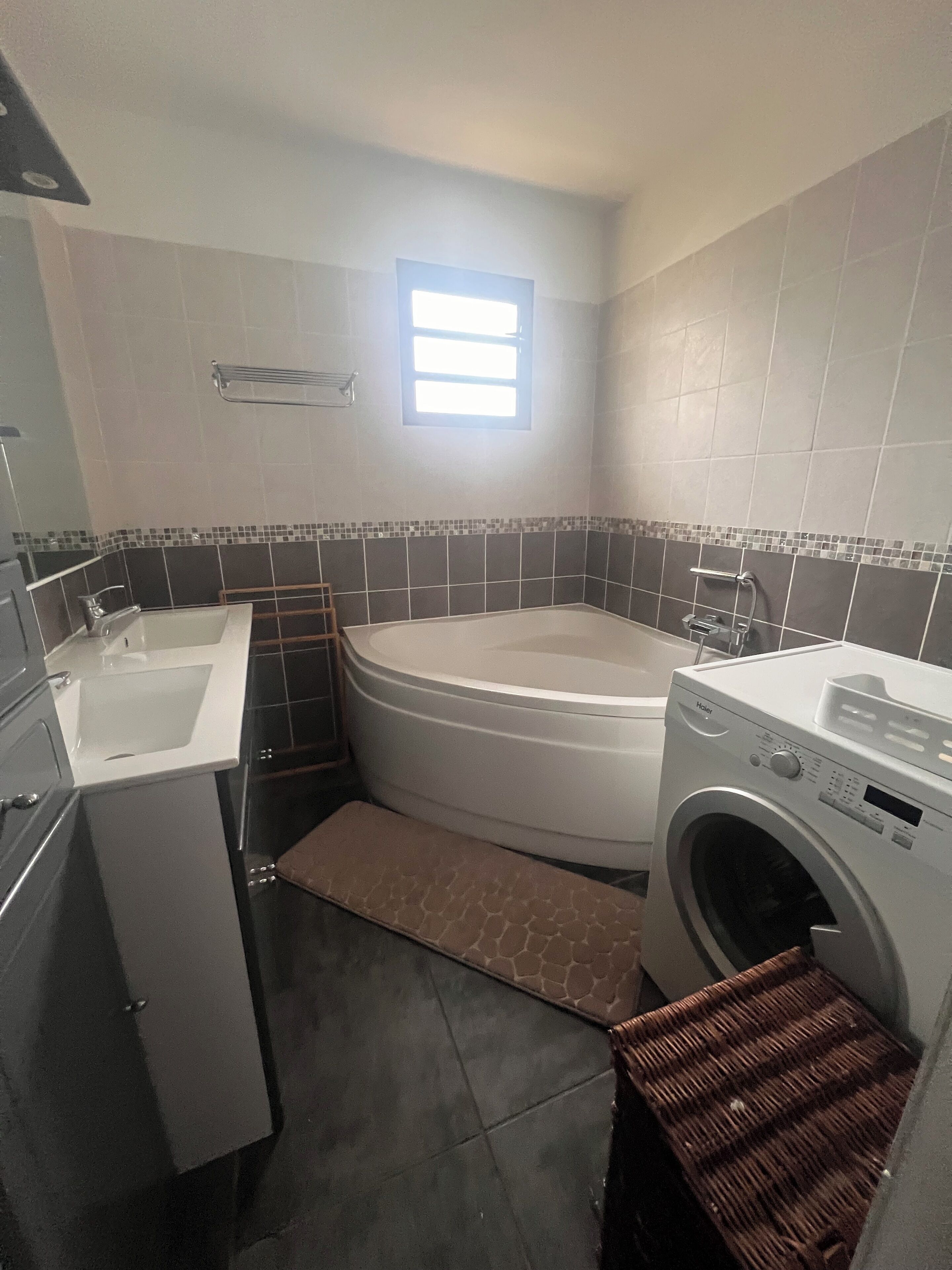 A compact bathroom with a bathtub, a washing machine, and a sink.