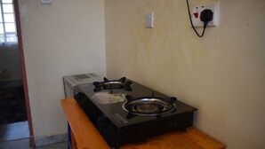 A kitchen with a gas stove, a bench, and a wall socket. - Humble Homes 1 bedroom Thika Town CBD access to Netflix,Fridge,wifi (thika)