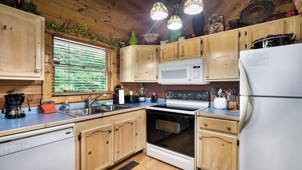 Una cocina con armarios de madera, microondas, estufa y refrigerador.