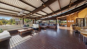 Un patio al aire libre con suelo de madera, zonas de estar y una pared de piedra.