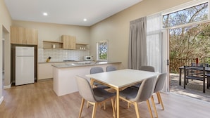 Una cocina moderna con una isla central, armarios de madera y un comedor con mesa y sillas.
