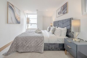 Un dormitorio moderno con una cama grande, una mesita de noche con lámpara y obras de arte en las paredes.