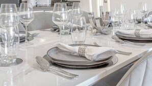 Ein stilvoller Essbereich mit einem Tisch aus weißem Marmor, gedeckt für eine Mahlzeit, mit klarem Glas, Besteck und einem dekorativen Mittelstück.