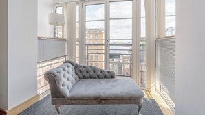Ein Zimmer mit großem Fenster, einem gepolsterten Sofa und einer Lampe.